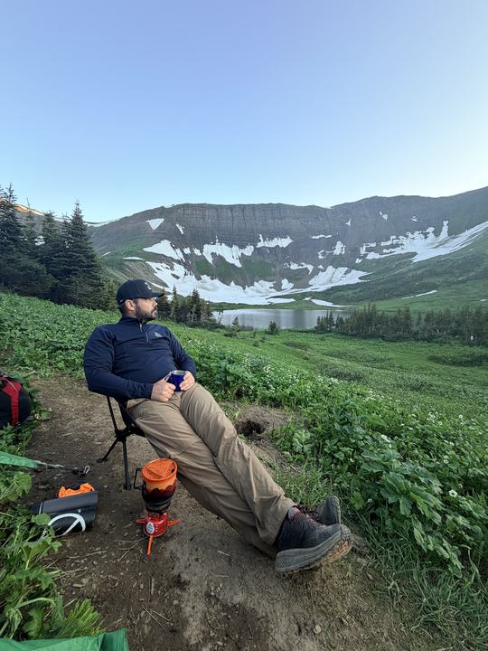 Ryan in a camp chair with a hot drink, looking out over Windfall Lake