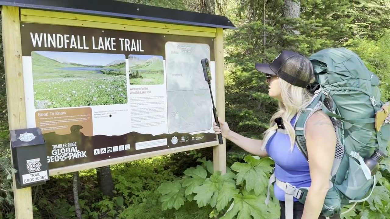 Stacie reading the Windfall Lake Trail sign at the trailhead in the Tumbler Ridge UNESCO Global Geopark